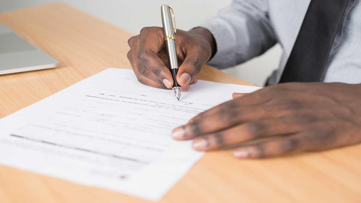 man signing application form