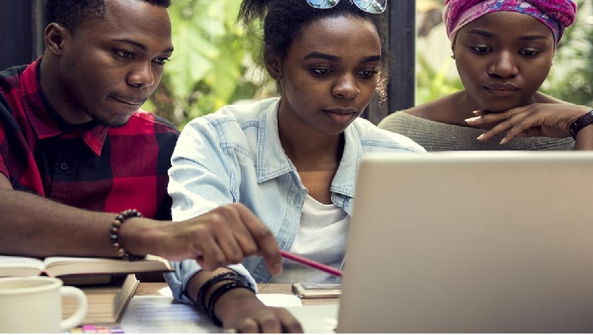 A group of young people watching a laptop 