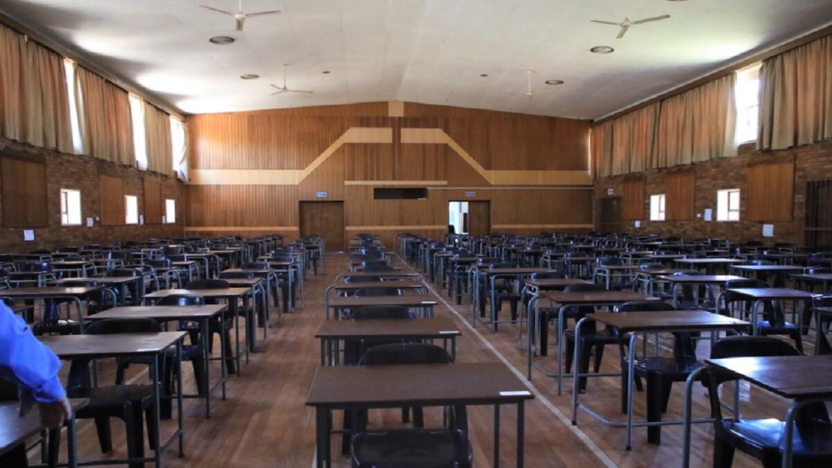 an exam hall filled with empty desks and tables organized in rows