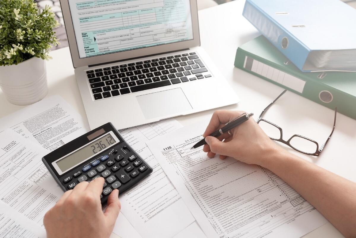 Laptop and calculator with a person seemingly busy with calculations. 