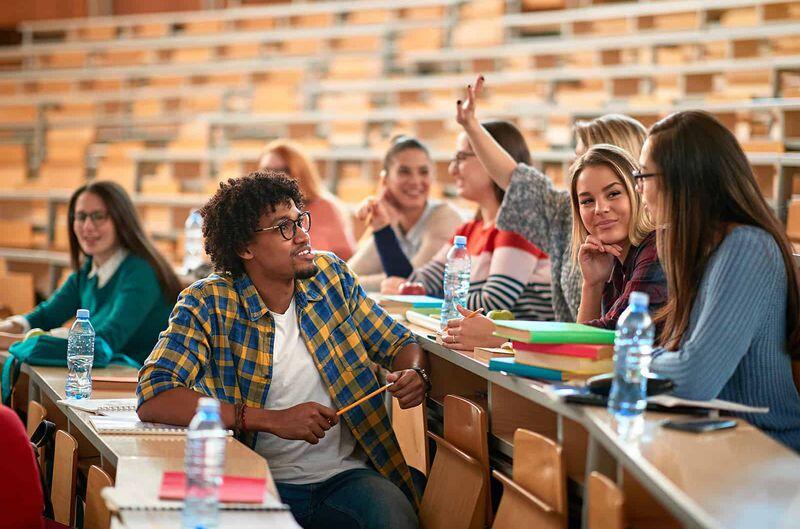Group of students in a class environment seemingly engage in discussion.