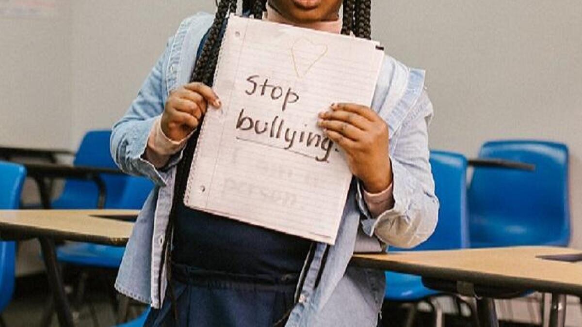 Girl Showing a Message Against Bullying in a Notebook