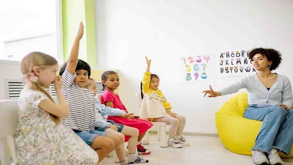 teacher giving lesson as learners raise their hands